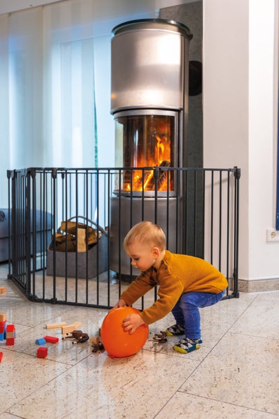 Wohnzimmer mit Kaminofen und Kindersicherungsgitter, ein Kind spielt mit einem Ballon