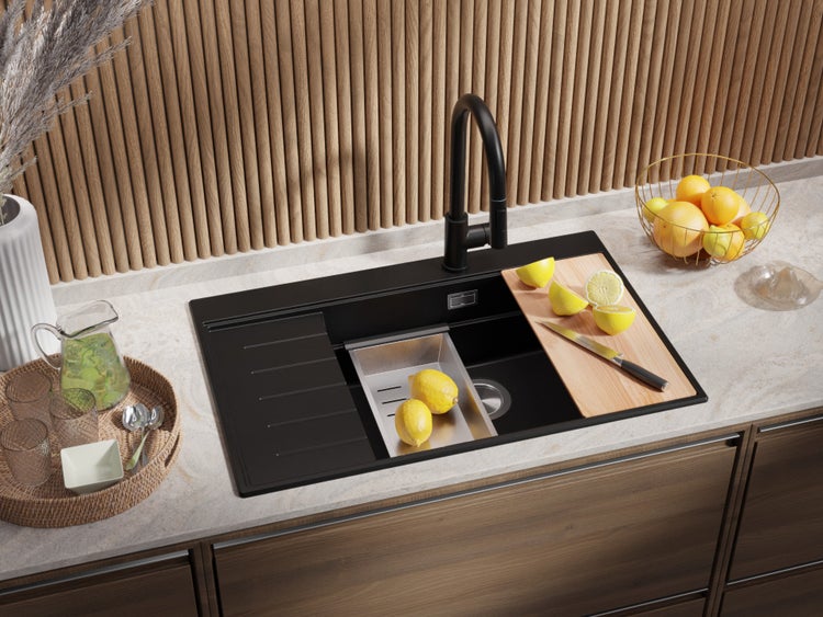 Schwarze Küchenspüle mit Abtropffläche, Schneidebrett und schwarzem Wasserhahn in einer Küchenszene.