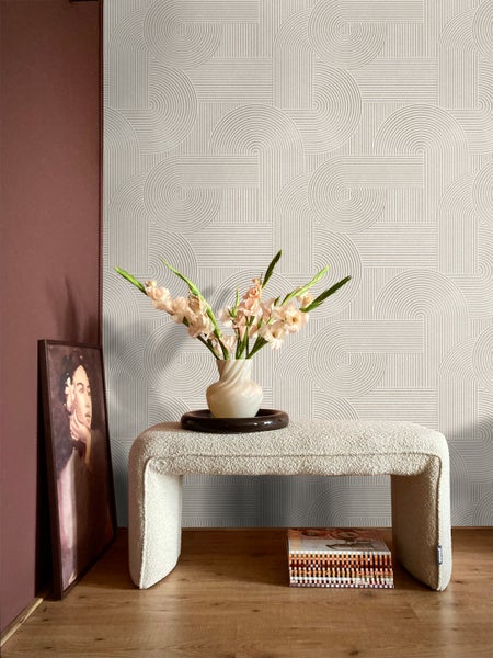 Raumansicht mit geometrischer Tapete, Hocker mit Blumenvase und gerahmtem Bild