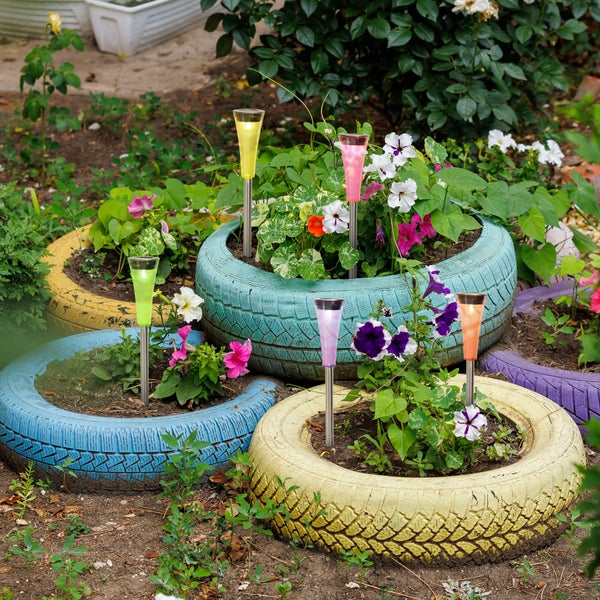 Gartenambiente mit bepflanzten, farbigen Reifenkästen und bunten Solarleuchten