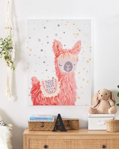 Dekoratives Kinderzimmer mit einem Llama Wandbild, Pflanze in einem Makramee-Hängekorb und einem Stofftierhasen auf einer Kommode
