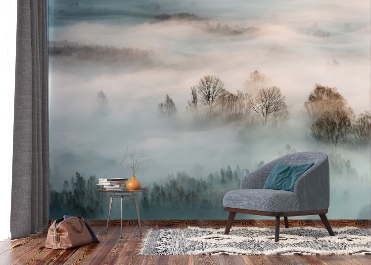 Wohnzimmer mit Fototapete einer nebligen Waldlandschaft, Sessel, Teppich und Beistelltisch