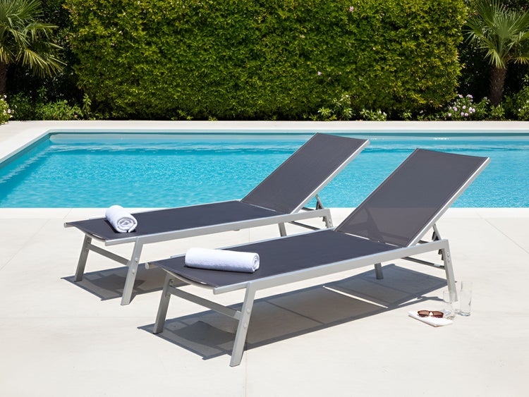 Zwei graue Sonnenliegen aus Metall mit Handtüchern am Pool