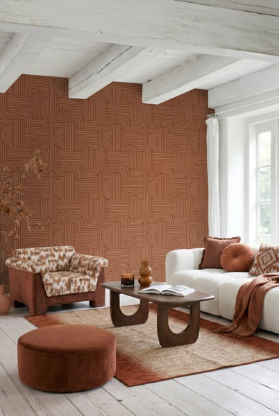 Modernes Wohnzimmer mit geometrisch gemusterter Tapete in Terrakotta, weißen Deckenbalken, weißem Sofa, gemustertem Sessel und Holztisch.