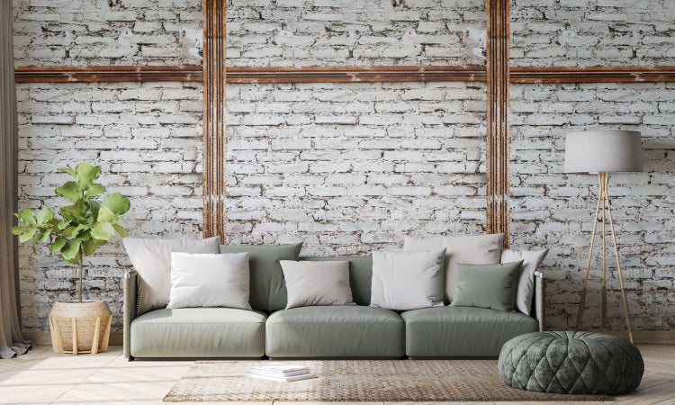 Wohnzimmer mit Sofa, Stehlampe und Zimmerpflanze vor einer Backsteinwand