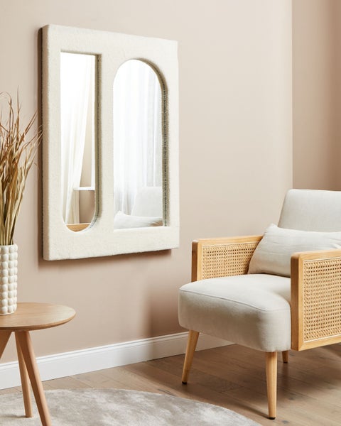 Dekorative Inneneinrichtung mit Spiegel, Sessel und Beistelltisch für ein helles Raumambiente.