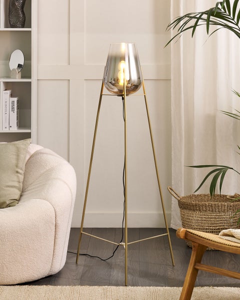 Stehlampe mit Glaskolben und goldenem Stativ im Wohnzimmer.