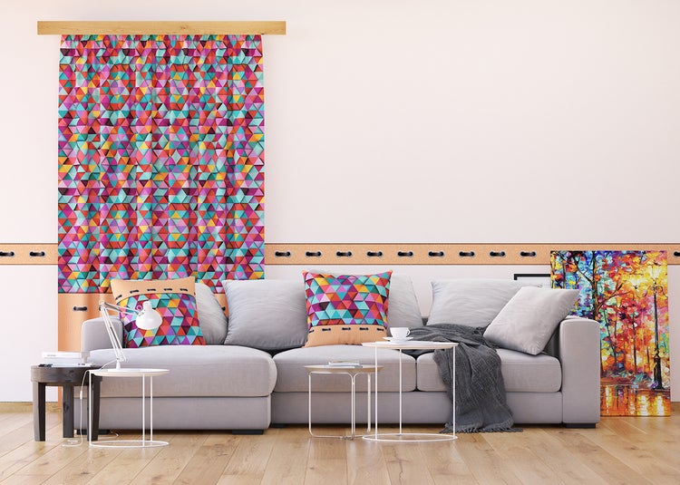 Wohnzimmer mit grauer Couch, Tisch, Lampe, Bild und Vorhang mit geometrischem Muster