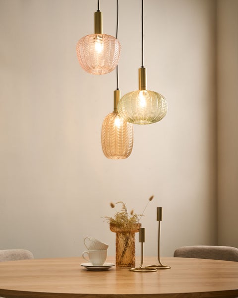 Szene mit drei farbigen Pendelleuchten aus Glas über einem Holztisch mit Dekoration