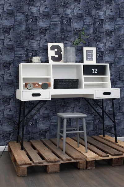 Schreibtisch mit Regalen, Stuhl und Dekorationsgegenständen vor einer Tapete mit Jeansmuster