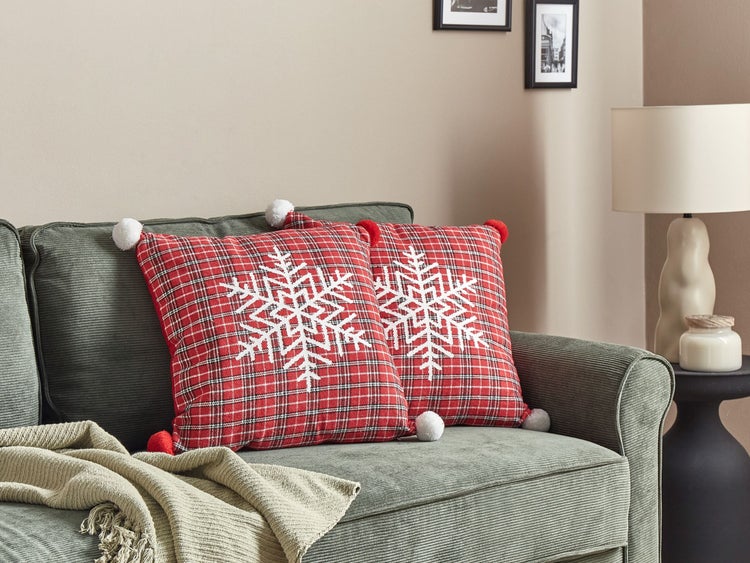 Dekorative rot karierte Kissen mit Schneeflockenmuster auf Sofa