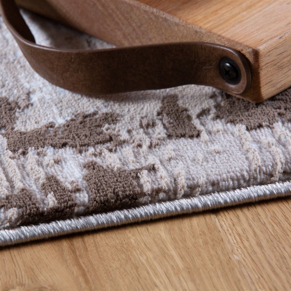 Nahaufnahme eines gemusterten Teppichs mit strukturierter Oberfläche und geketteltem Rand.