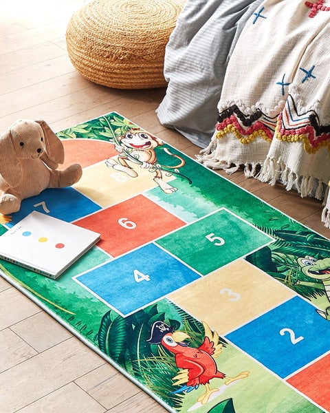 Farbenfroher Kinderteppich mit Hüpfspiel Design, Dschungeltieren und Zahlen auf Holzboden in einem hellen Kinderzimmer.