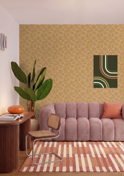 Helles Wohnzimmer im Retro-Stil mit gemusterter Tapete, rosa Polstersofa, Holzschreibtisch, Zimmerpflanze und gestreiftem Teppich.