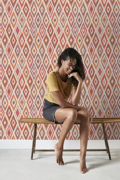 Raum mit gemusterter Tapete und einer Frau, die auf einer Bank sitzt