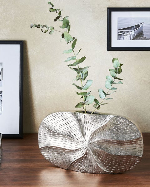 Dekorative Blumenvase aus Metall mit Muster auf einem Tisch