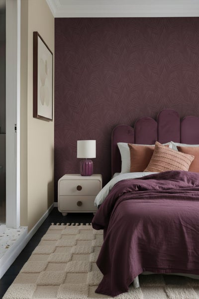 Ein Schlafzimmer mit einem Bett, einem Nachttisch und einer gemusterten Tapete.