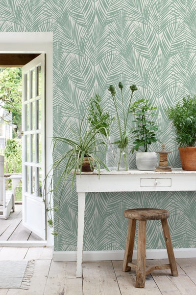Zimmer mit Blättertapete, weißem Tisch und Pflanzen