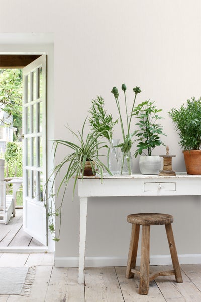 Helle Inneneinrichtung mit Pflanzen auf einem Tisch und einem Hocker