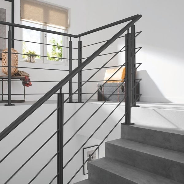 Treppe mit schwarzem Geländer aus Metallstäben in einem hellen Treppenhaus.