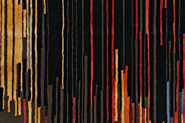 Nahaufnahme eines Teppichs mit einem abstrakten Muster aus vertikalen Streifen in verschiedenen Laengen und Farben.