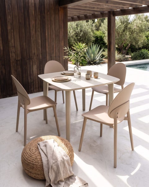 Modernes Garten-Essset mit quadratischem Tisch und vier Stühlen auf einer hellen Terrasse neben einem Pool und einer Holzwand.