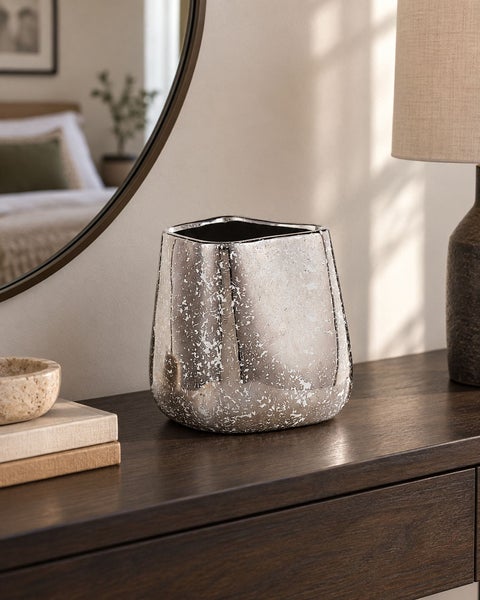 Dekorative Vase mit strukturierter Oberfläche in metallischer Optik auf einer Holzkommode.