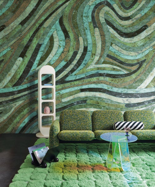 Wohnzimmer mit Sofa, Teppich, Regal und gemusterter Tapete für ein modernes Wohnambiente.