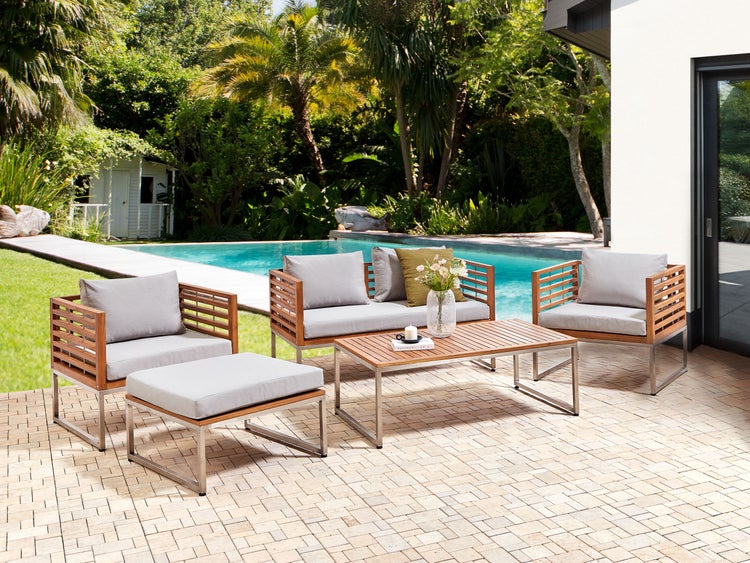 Gartenmöbelset mit Sesseln, Sofa, Fußhocker und Tisch auf einer Terrasse neben einem Pool.