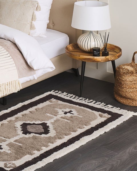 Rechteckiger Badteppich in Beige und Grau mit geometrischem Ethno-Muster, Rautenmotiv und Fransen an den Seiten.