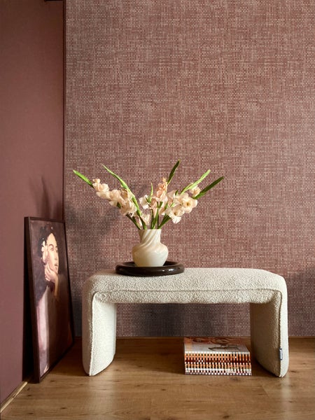 Dekoratives Interieur mit Bank, Vase und Gemälde vor einer strukturierten Wand.