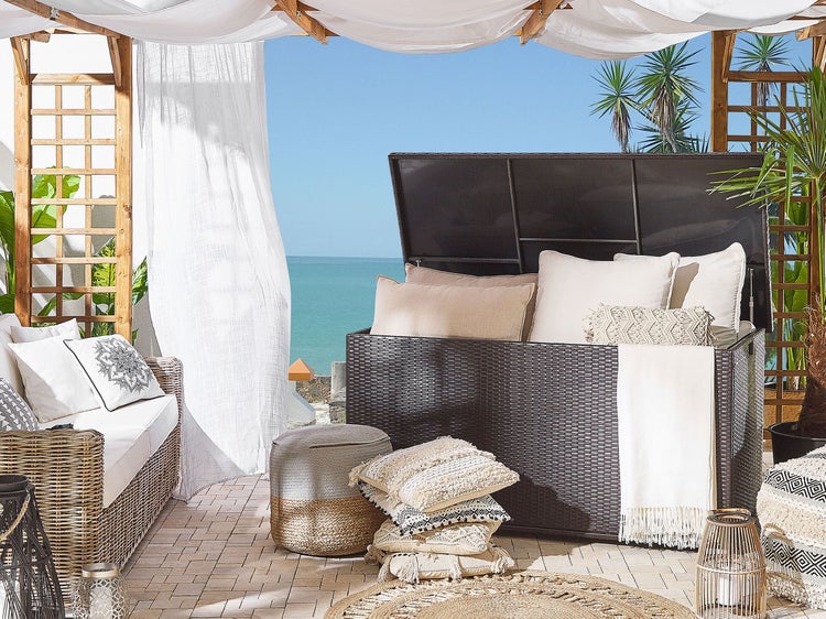 Wohnzimmer im Freien mit Rattanmöbeln, Kissen und Stauraumtruhe