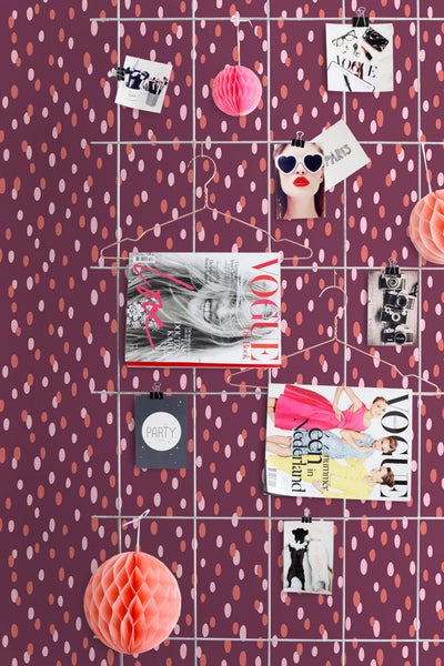 Dekorative Wand mit Zeitschriften, Fotos und Papierornamenten.