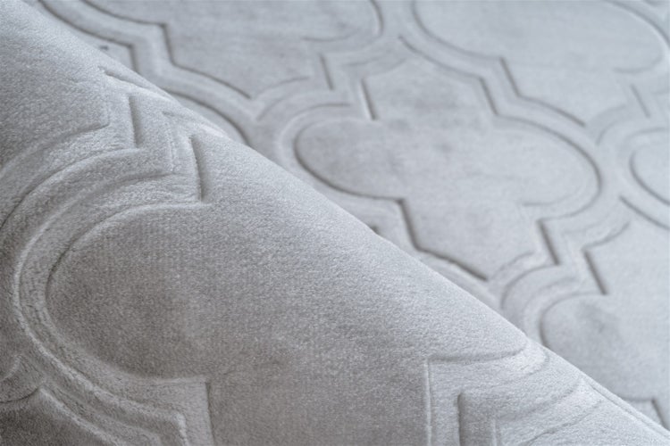 Nahaufnahme eines weichen Teppichs mit geprägtem Ornamentmuster und flauschiger Textur.