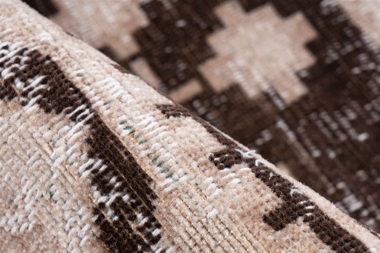 Nahaufnahme eines gewebten Teppichs in Braun und Beige mit geometrischem Muster und feiner Textur.