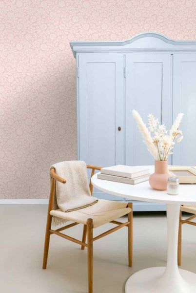 Helles Zimmer mit gemusterter Blumentapete, einem hellblauen Holzschrank, einem Holzstuhl mit Decke und einem runden weißen Tisch.