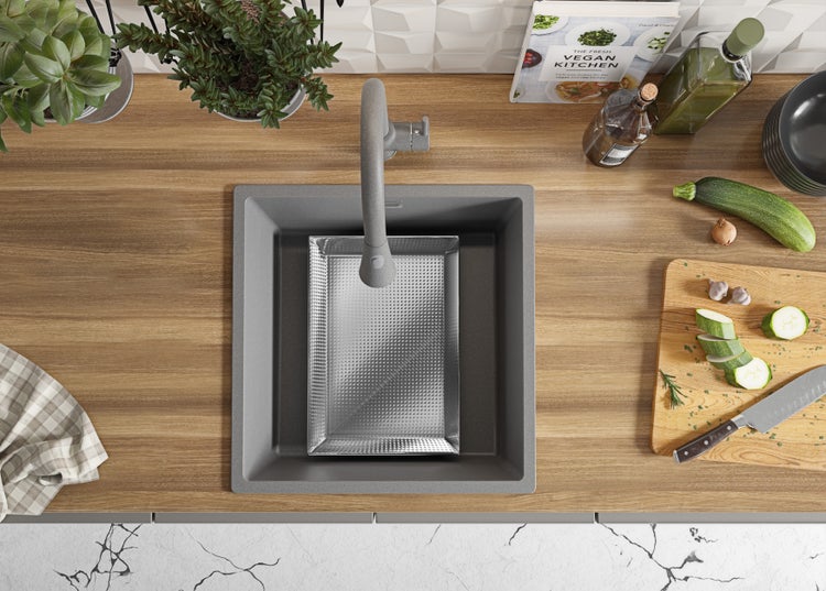 Küchenszene mit Spüle, Armatur, Schneidebrett mit Zucchini und Kräutern, Kochbuch und dekorativen Elementen auf einer Holzarbeitsplatte