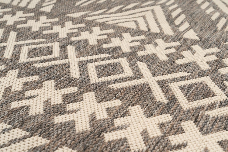 Detailansicht eines grau-beigen Flachgewebe-Teppichs mit geometrischem Muster.