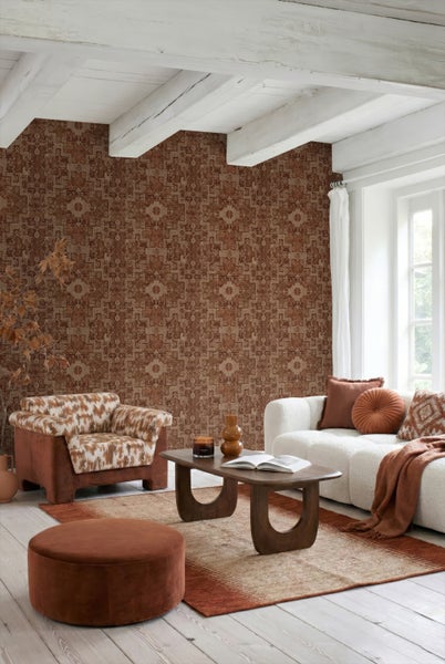 Helles Wohnzimmer mit gemusterter Tapete, weißem Sofa, gemustertem Sessel und Holztisch. Mit weißen Deckenbalken und rustikalem Stil.