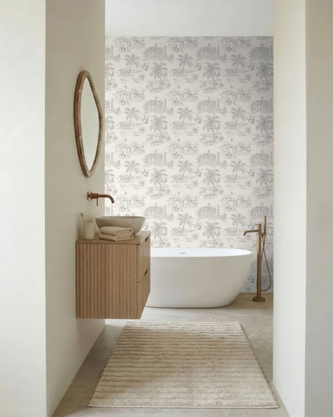 Helles Badezimmer mit freistehender Badewanne, Safari-Mustertapete, hölzernem Waschtisch und Armaturen in Bronze.