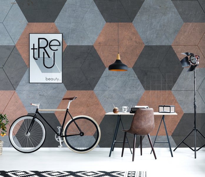 Fototapete mit hexagonalem Muster in Grau und Kupfer in einem Raum im Industrial-Style mit Schreibtisch und Fahrrad.