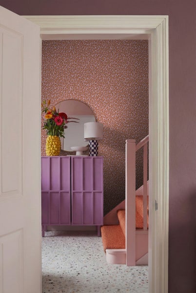Flur mit gemusterter Tapete, Kommode, Spiegel und Treppe