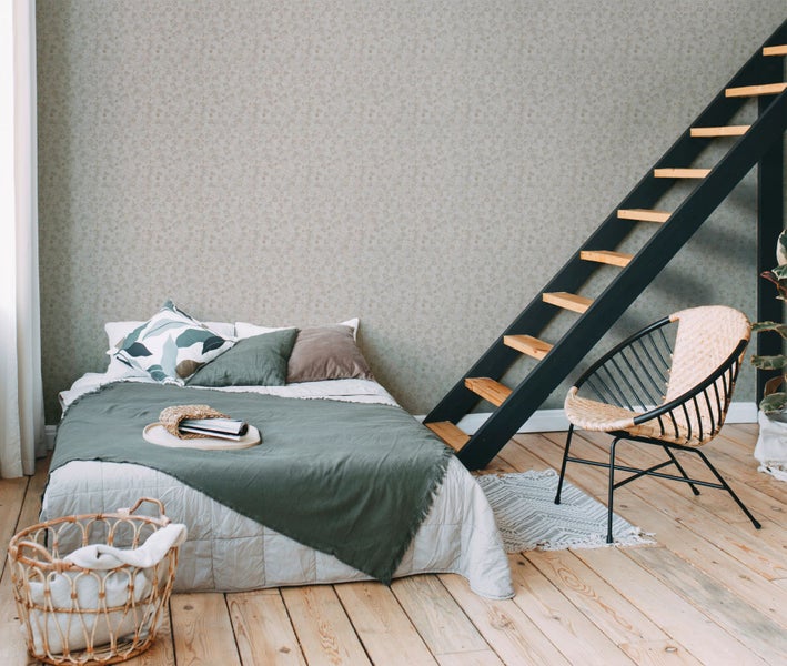 Dekoratives Zimmer mit Schreibtisch, Stuhl, Lampe und Fahrrad vor einer Tapete mit Grasmuster