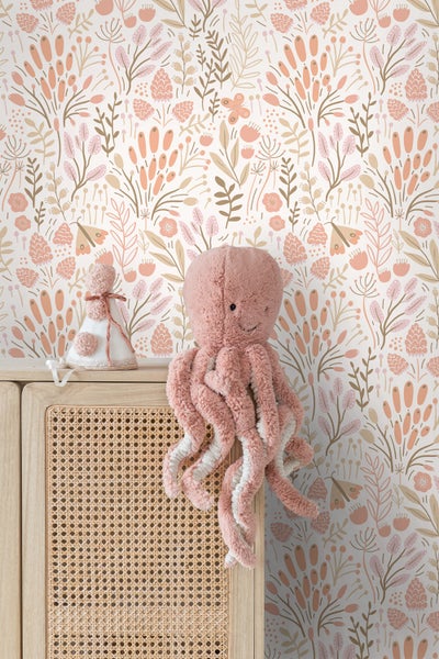 Mädchen vor Tapete mit floralem Muster im Kinderzimmer