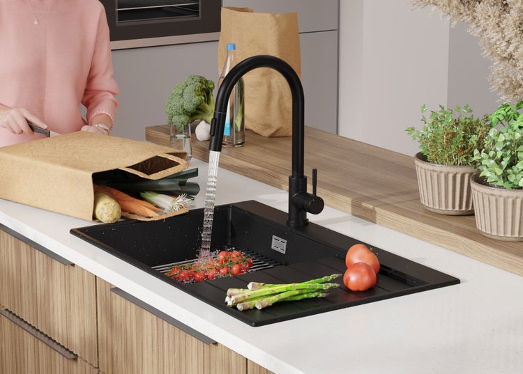 Schwarze Küchenspüle mit Armatur, Gemüse und Einkaufstasche