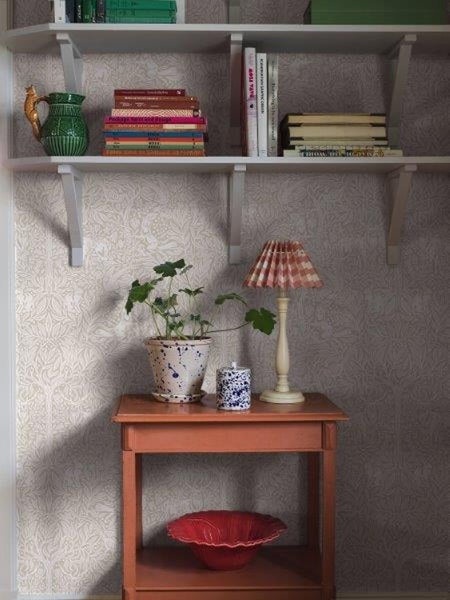 Dekoratives Interieur mit Bücherregal, Tischlampe und Zimmerpflanze für eine gemütliche Raumatmosphäre.