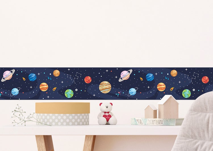 Selbstklebende Tapetenbordüre für Kinderzimmer mit Weltraum-Motiv, Planeten und Sternen, angebracht über einem Schreibtisch.