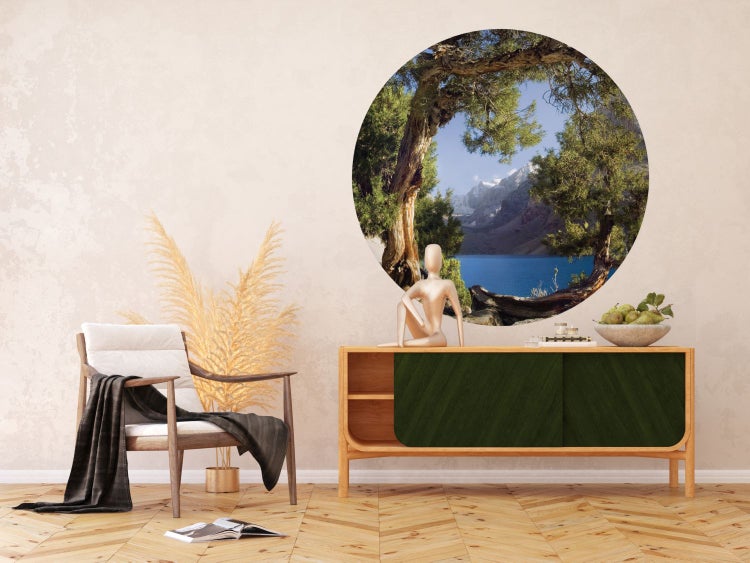 Raumgestaltung mit Sessel, Kommode und runder Bergsee-Wanddekoration für ein helles Ambiente