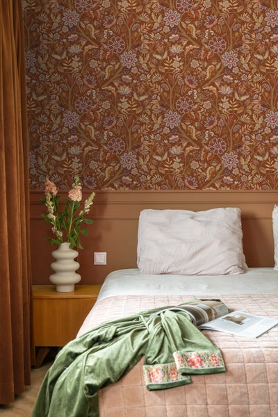 Eine Person hält ein Smartphone, das eine App zur Visualisierung von Tapeten in einem Wohnraum zeigt