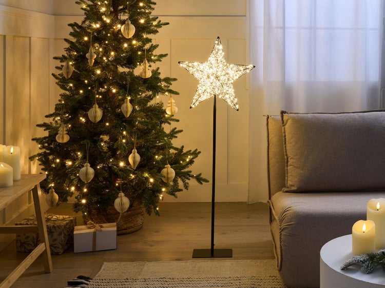 Weihnachtlich dekorierter Wohnraum mit Weihnachtsbaum, beleuchtetem Stern und Kerzen